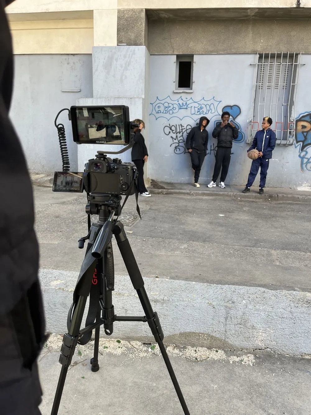 Caméra sur trépied filmant un groupe de jeunes devant un mur